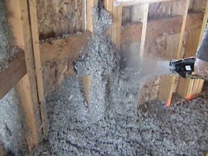 Loose-fill cellulose insulation being blown into a wall.