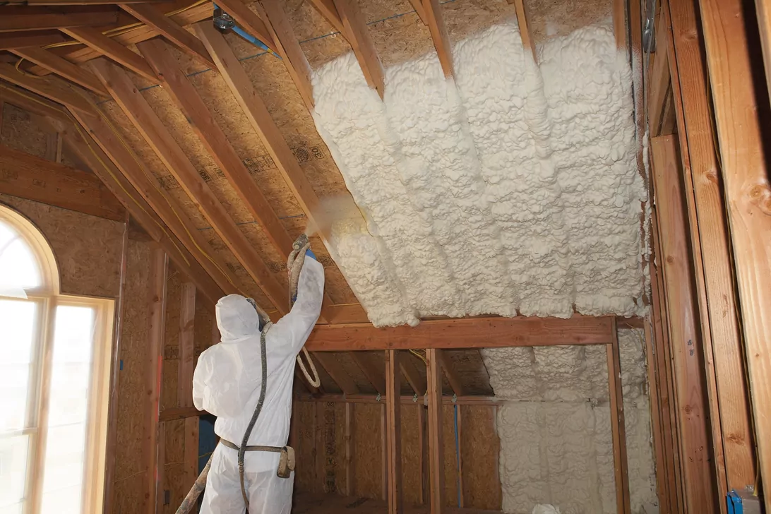 Insulation technician installing spray foam insulation in an attic ceiling