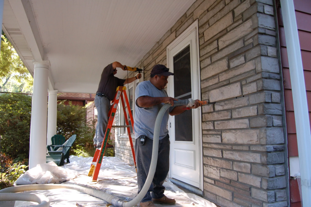 Insulation technicians installing retrofit insulation in a home